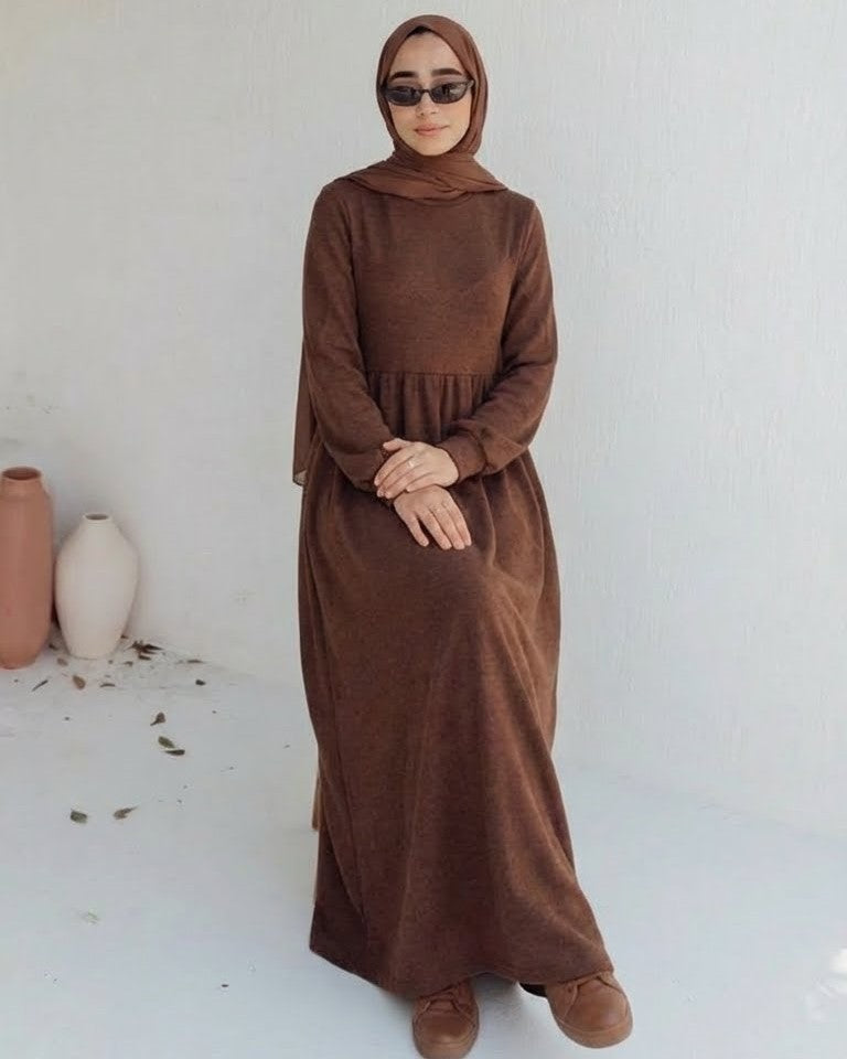 مودل ترتدي فستان طويل مودست باللون بني من ضي Dhai، تصميم واسع ومحتشم بأكمام طويلة مع حجاب مطابق، إطلالة أنيقة وبسيطة على خلفية بيضاء.
فستان برجاندي 
مودست فاشون
دريس ميلتون
دريس ملتون