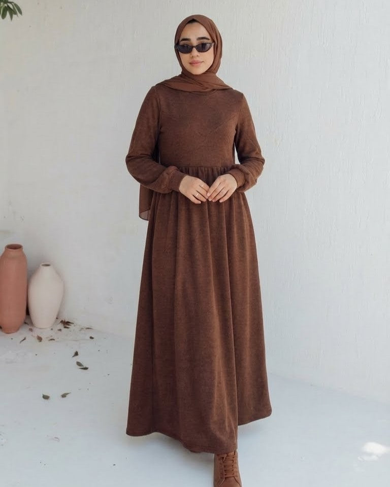 مودل ترتدي فستان طويل مودست باللون بني من ضي Dhai، تصميم واسع ومحتشم بأكمام طويلة مع حجاب مطابق، إطلالة أنيقة وبسيطة على خلفية بيضاء.
فستان برجاندي 
مودست فاشون
دريس ميلتون
دريس ملتون